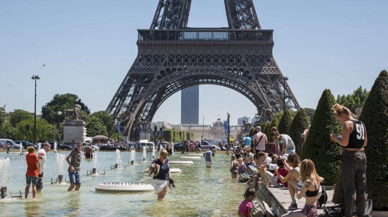 Multitud de personas se refrescan en las fuentes de los jardines del Trocadero junto a la Torre Eiffel en París este viernes