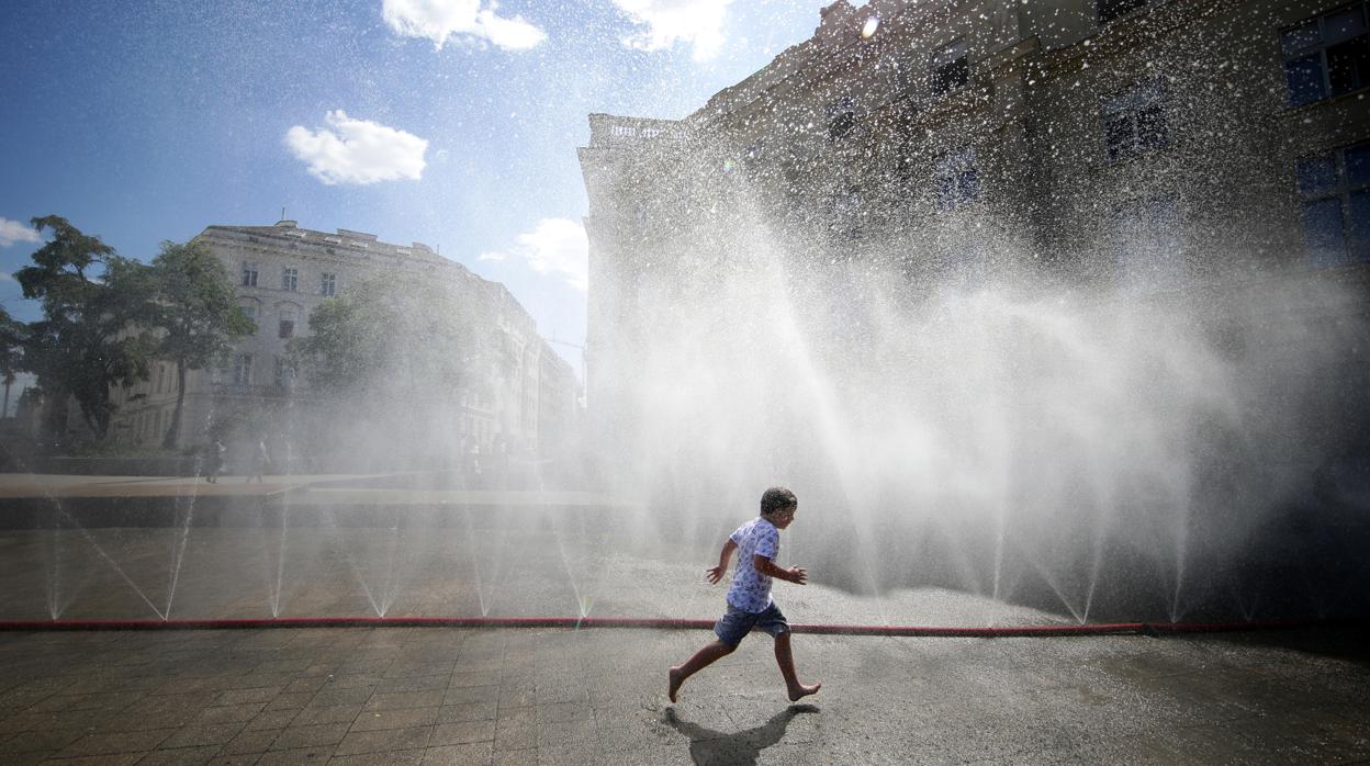 Un niño corre bajo aspersores de agua durante la ola de calor en Viena, Austria