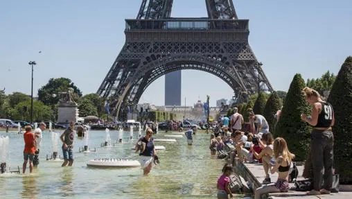 Multitud de personas se refrescan en las fuentes de los jardines del Trocadero junto a la Torre Eiffel en París
