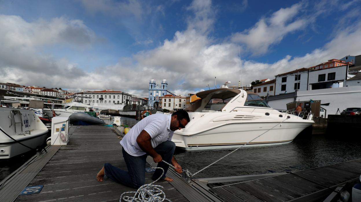 un hombre refuerza con cuerdas el amarre de su barco en un puerto antes de la llegada del huracán Lorenzo en Angra do Heroismo en las islas Azores