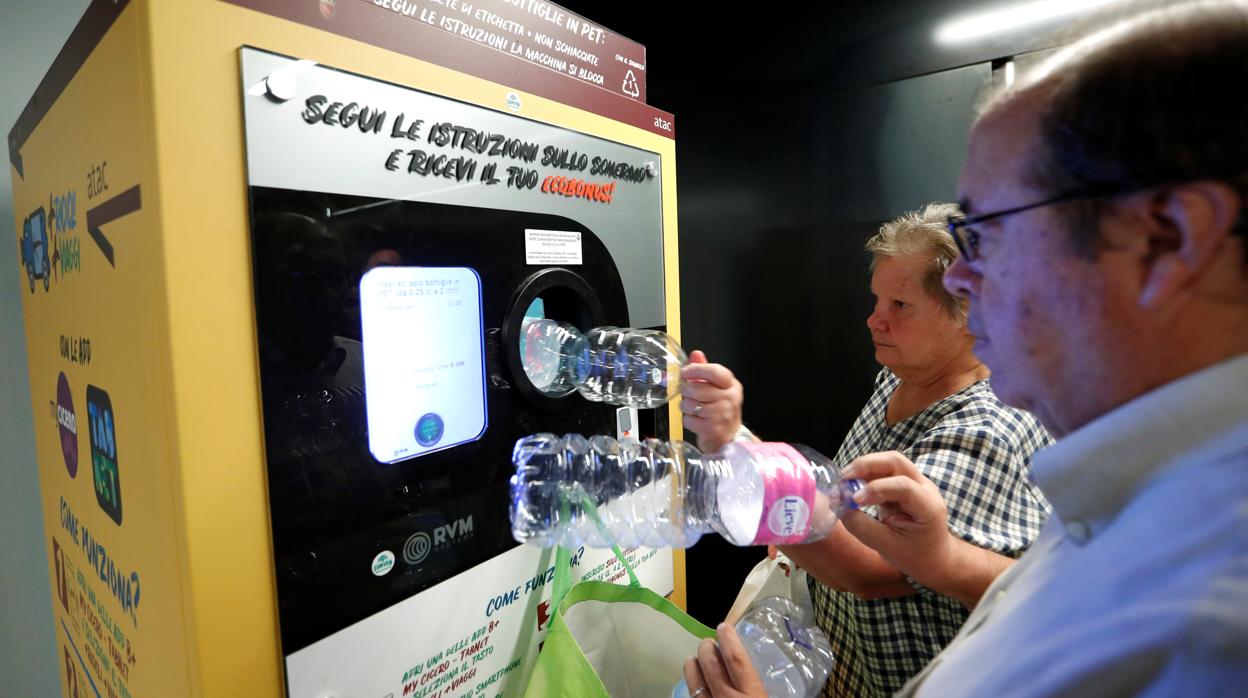 Varias personas reciclan botellas de plástico en una de las máquinas puestas en el metro de Roma