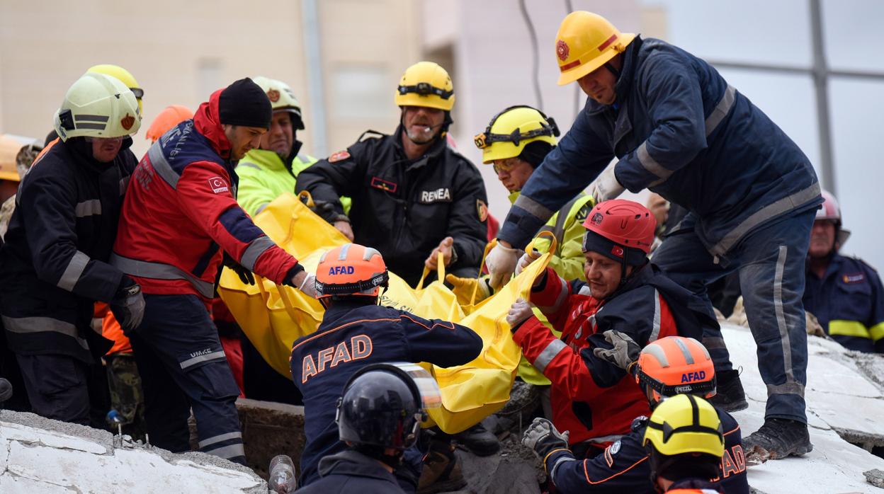 Equipos de rescate y bomberos cargan con el cuerpo de una víctima encontrada bajo los escombros en Durres