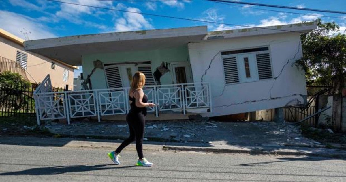 Una mujer pasa junto a una casa dañada en Guanica, Puerto Rico