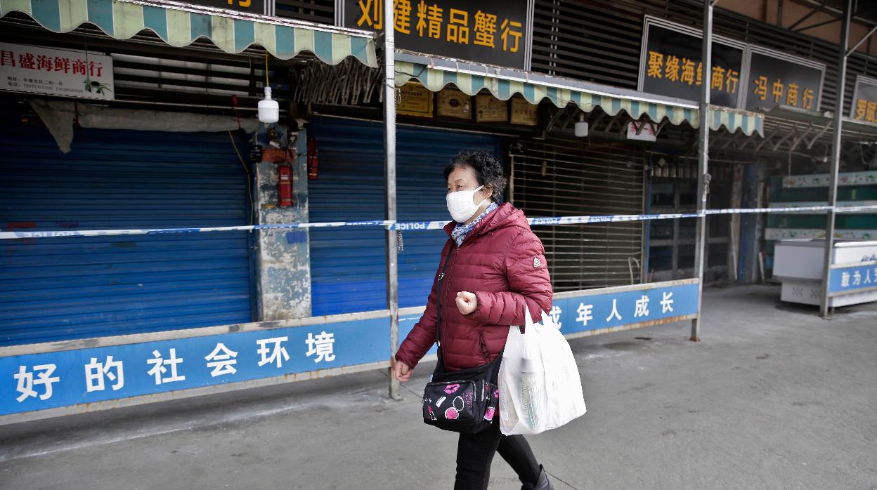 Una mujer pasea con mascarilla por las calles de la ciudad china de Wuhan