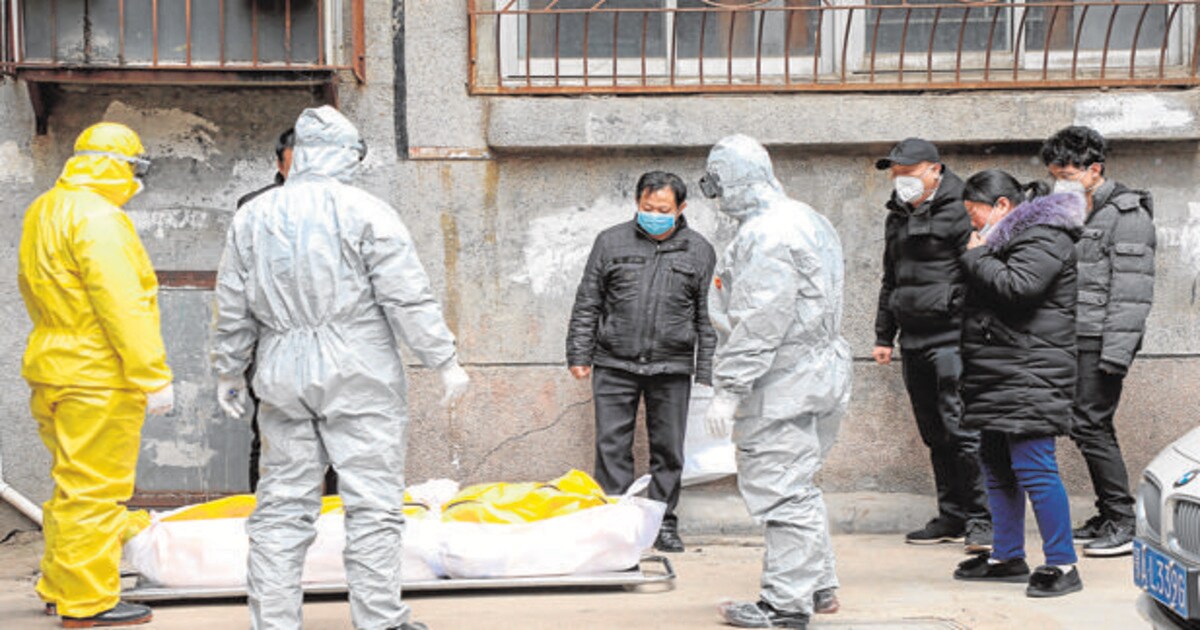 Trabajadores de la funeraria trasladan el cuerpo de una persona fallecida por coronavirus en su casa en Wuhan