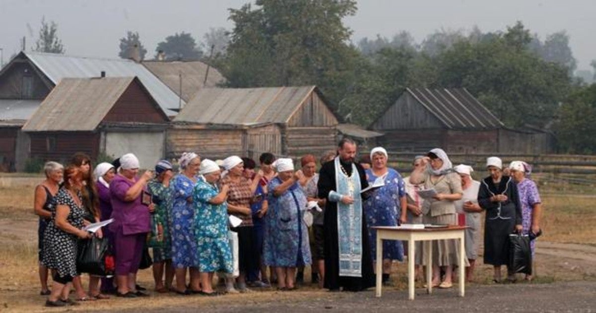 Un saceerdote ortodoxo reza junto a un grupo de vecinos después de que un incendio arrasara parte del pueblo de Kriusha, a unos 270 kilómetros al sureste de Moscú (Rusia),