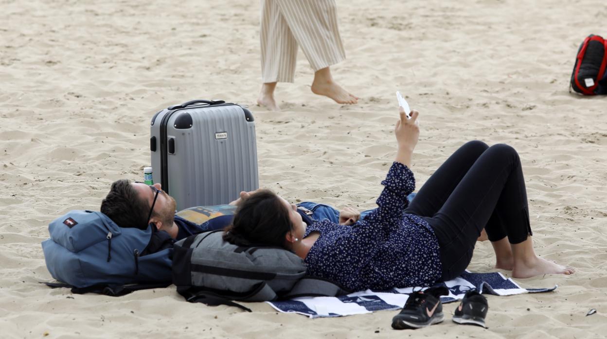 Ambiente ayer en la playa de El Postiguet, en Alicante. En la imagen, madrileños llegados en tren y autobús ayer se tumban en el arenal pese a la crisis por el coronavirus