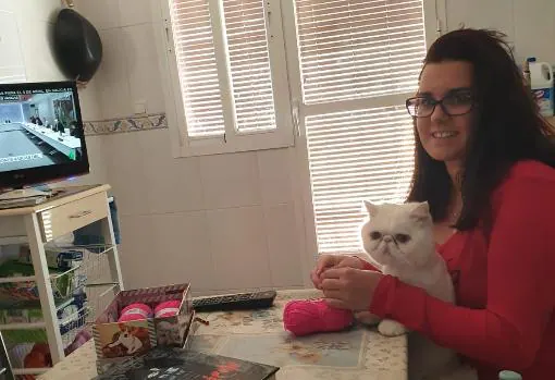 Pilar, junto a su gato, en la cocina de su casa haciendo ganchillo