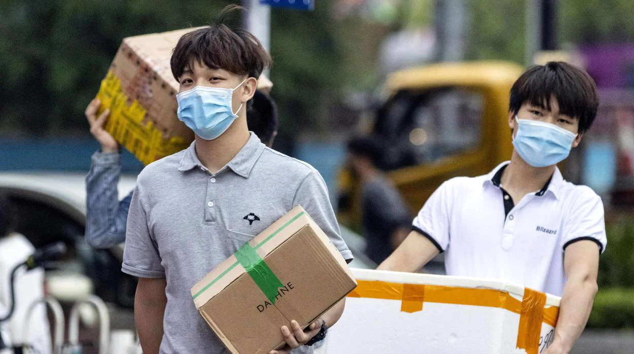 Ciudadanos en China cargan paquetes y se aprovisionan de víveres en estos tiempos de dificultades