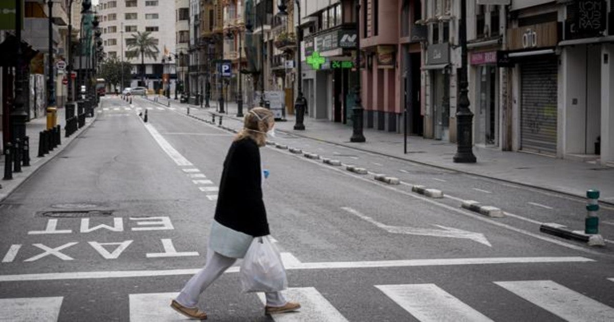 Una ciudadana de la tercera edad recorre una calle vacía por el contagio del coronavirus, en Valencia