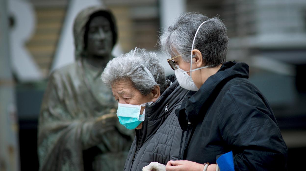 Una anciana, protegida con una mascarilla contra el coronavirus, camina por la calle