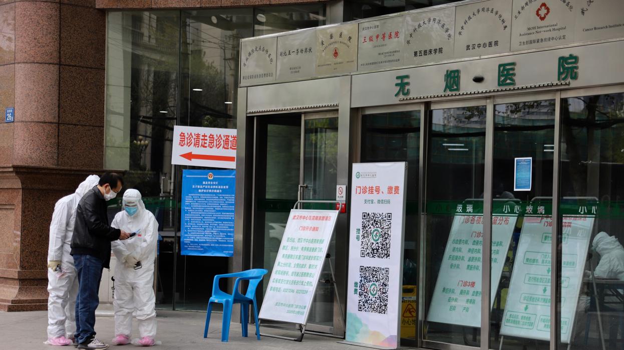 Pertrechados con monos blancos de protección contra el coronavirus, los enfermeros controlan el acceso al Hospital Central de Wuhan