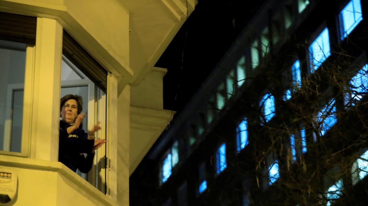 Una mujer aplaude sola esta noche desde la ventana de su casa en Madrid