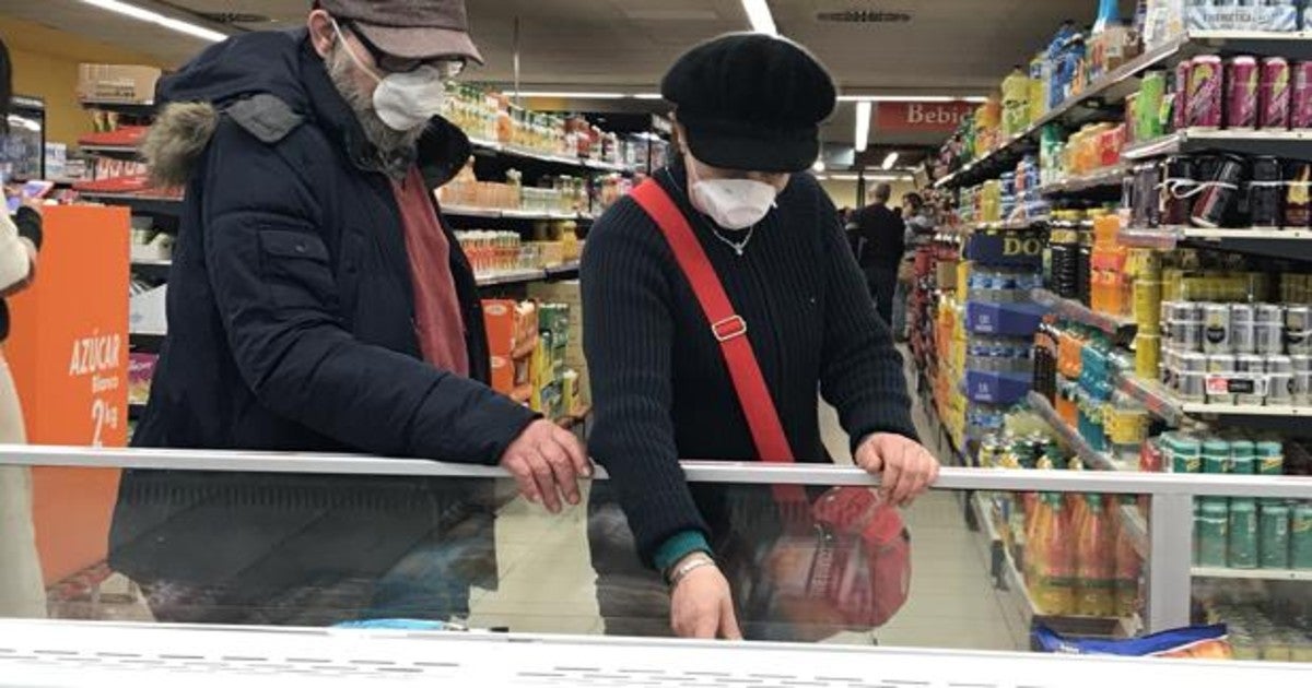 Dos personas compran en un supermercado cumpliendo con las medidas de protección