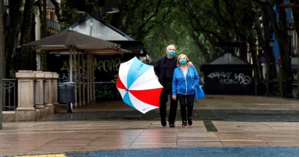 Una pareja pasea con mascarilla quirúgica