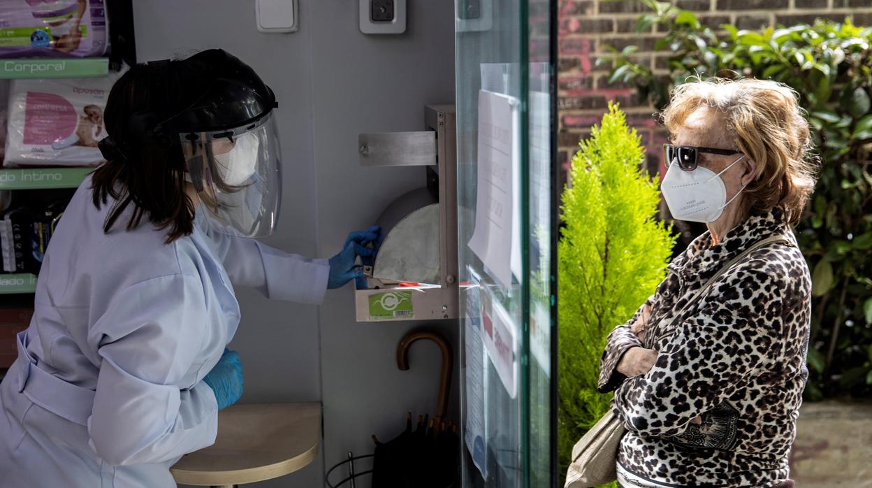 Una persona recoge su mascarilla en una farmacia de Madrid