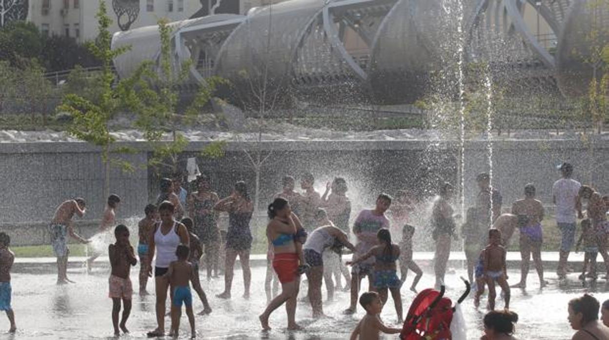 Un grupo de personas se refresa en las fuentes de Madrid Río por la ola de calor durante el verano de 2019