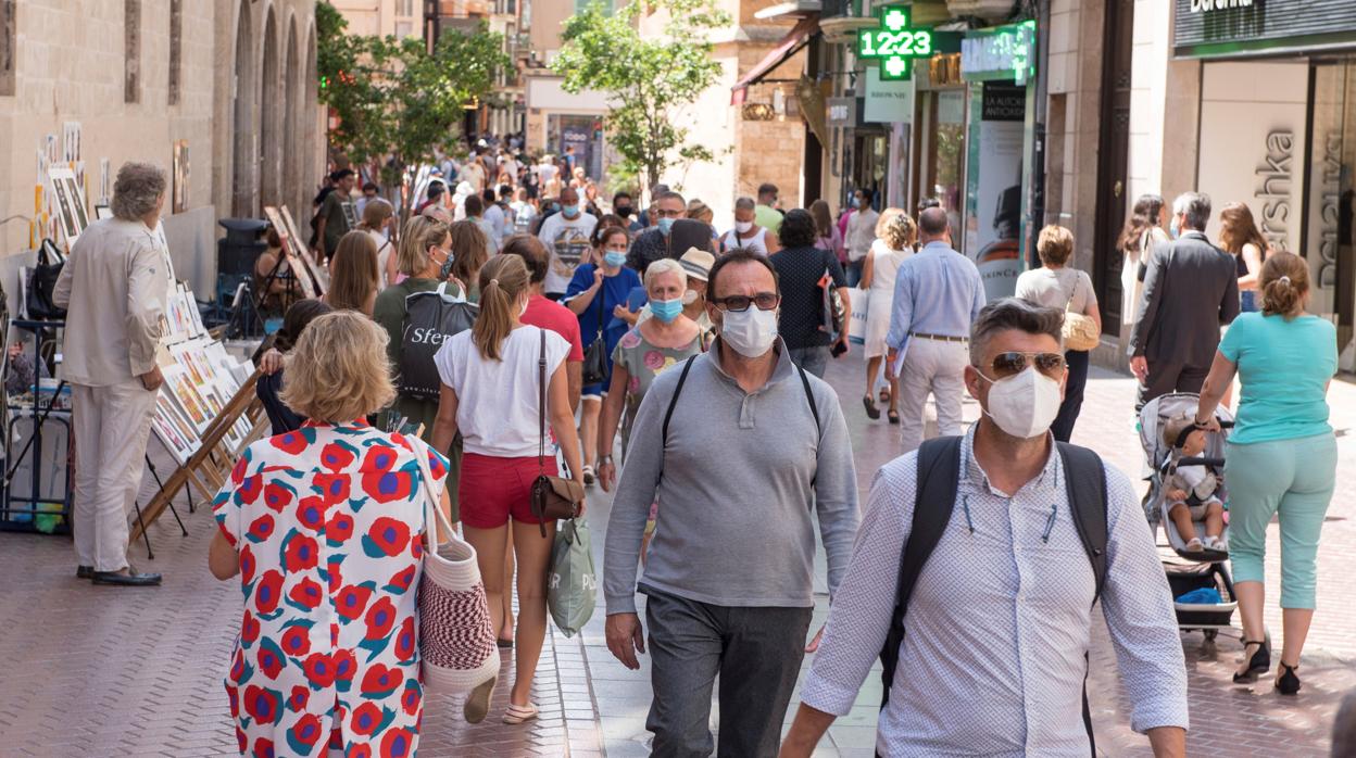 Transeúntes se protegen con mascarillas por las calles de Palma de Mallorca