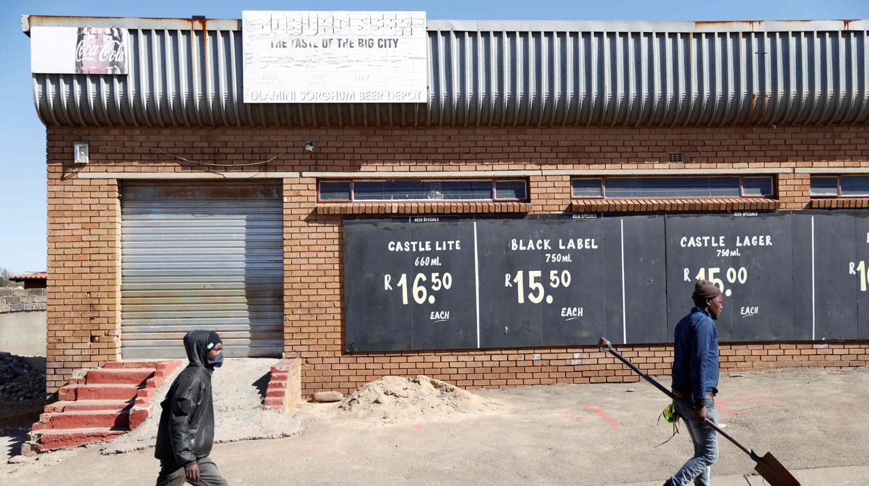 Dos personas caminan en una calle de Soweto, ayer, donde todos los locales y tiendas están cerrados por temor al coronavirus