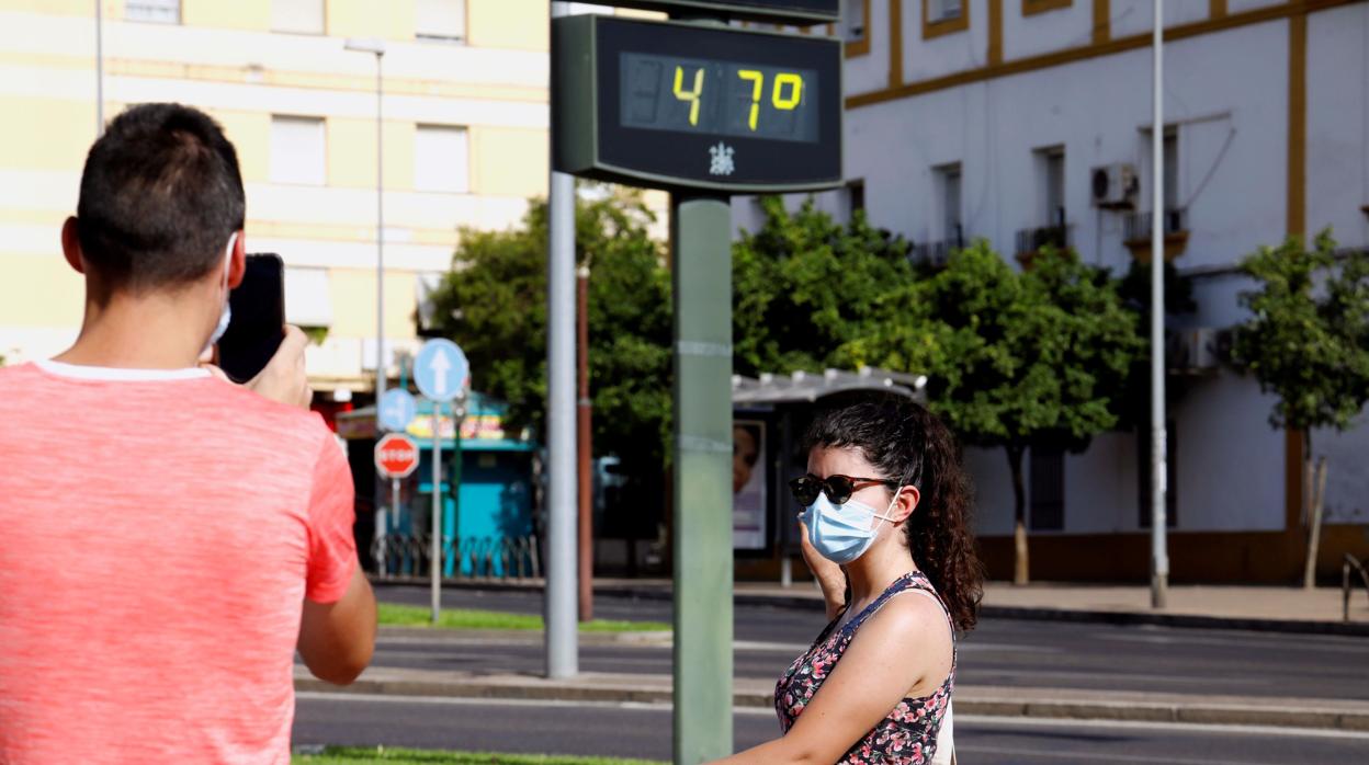 Unas personas se fotografían junto a un termómetro digital a pleno sol que marca 47 grados