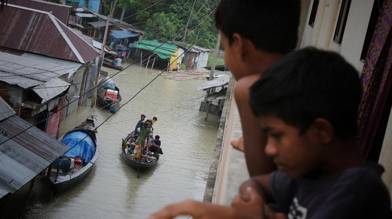 Las personas usan botes en una carretera sumergida durante las inundaciones del monzón