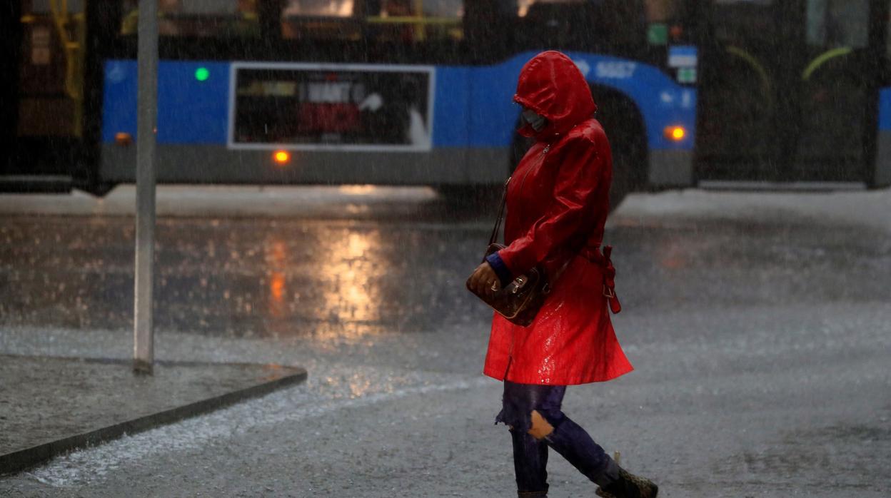 Una mujer camina por la calle durante la tormenta registrada la mañana de este jueves en Madrid