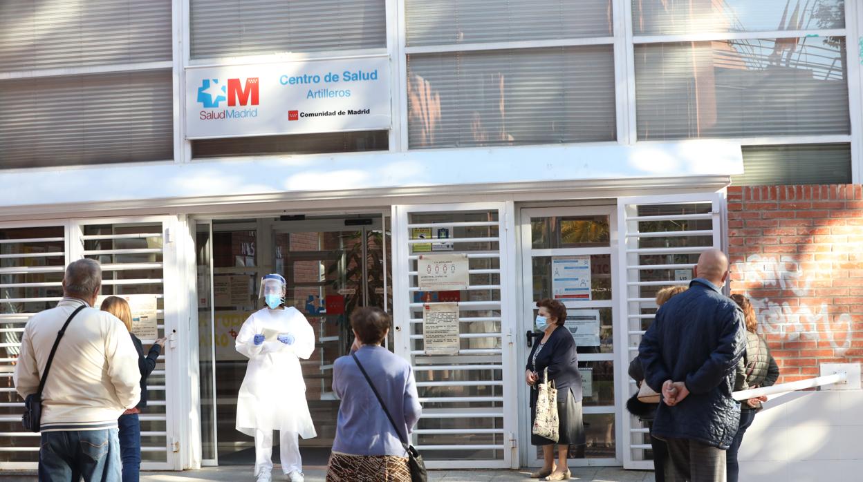 Una sanitaria sale a atender a las numerosas personas que hacen cola en un Centro de Salud de Madrd