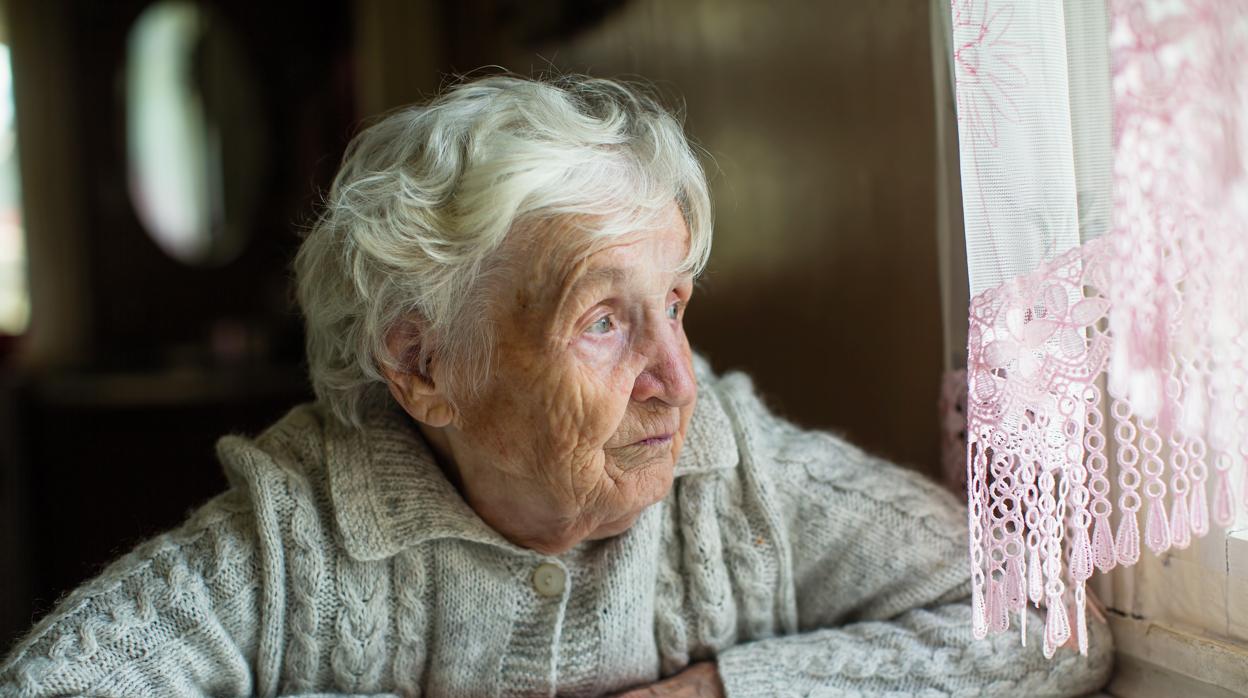 Una anciana mira hacia la ventana durante el confinamiento