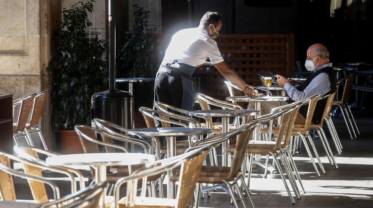 Un camarero atiende a un cliente en un local de la Plaza Real de Barcelona, tras la decisión del Govern de cerrar bares y restaurantes en Cataluña durante 15 días