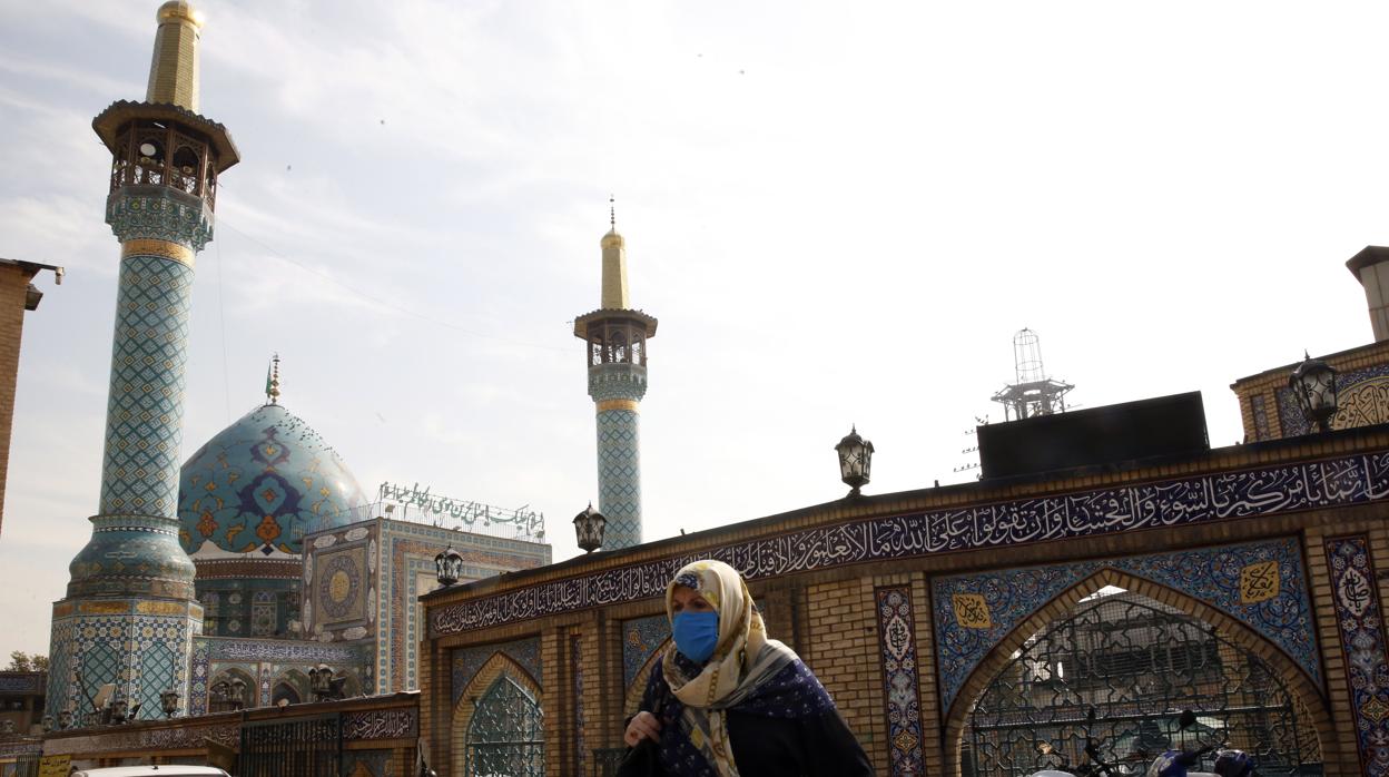 Una mujer iraní con una mascarilla pasa junto al santuario de Saleh en Teherán, Irán