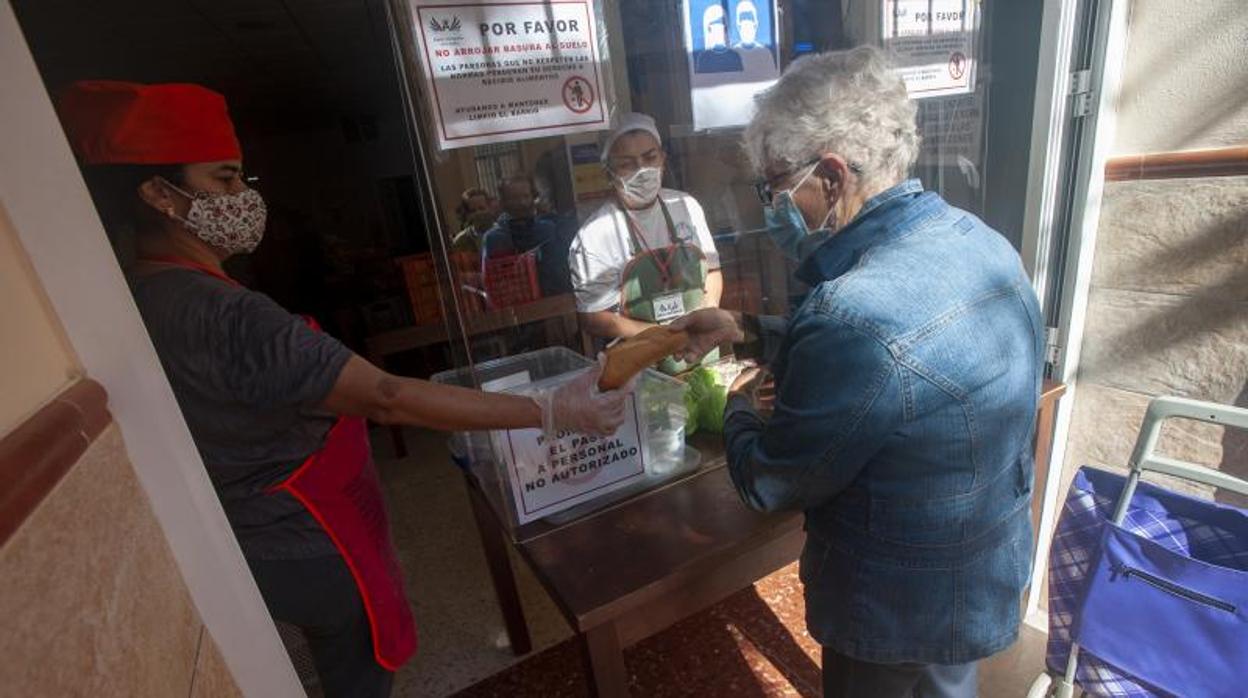 Una persona recibe alimentos en la Asociación Ángeles Malagueños de la Noche en Málaga