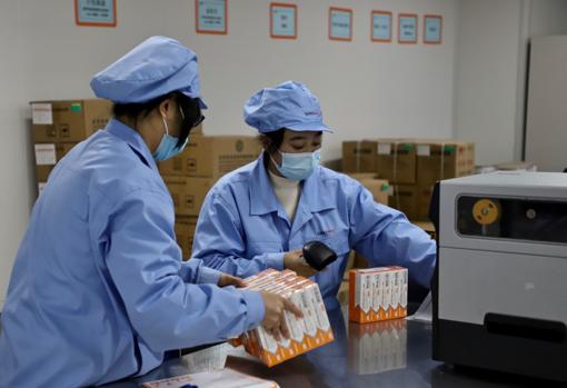 Dos empleadas de Sinovac empaquetan las vacunas contra el coronavirus, que se está inoculando de emergencia antes de ser aprobada