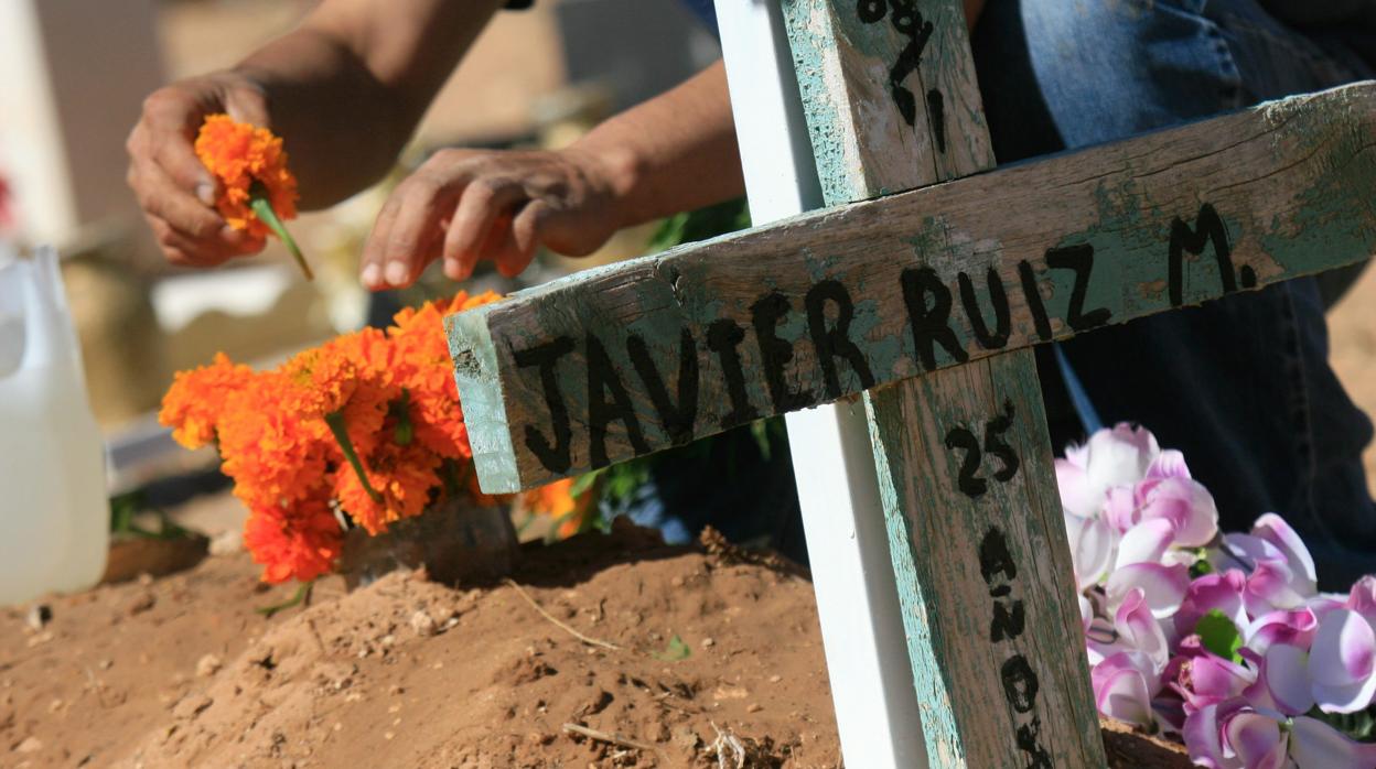 Una persona adorna conflores la tumba de un pariente el día de los difuntos