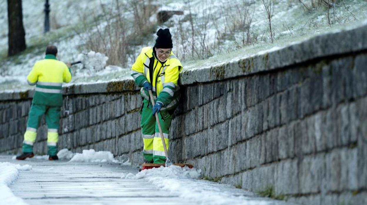 Operarios retiran la nieve y el hielo acumulado en las aceras en una calle de Ávila donde se han registrado temperaturas de 6,5 grados bajo cero durante la madrugada