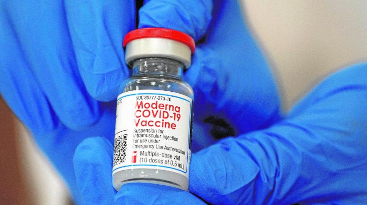 Un empleado de Moderna enseña uno de los viales de la vacuna