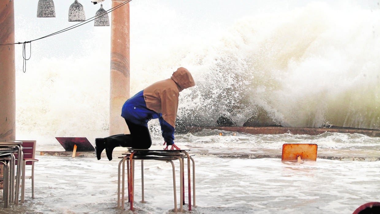 Una persona subida a una mesa del mobiliario de una terraza ante las inundaciones por la borrasca Filomena. En Málaga