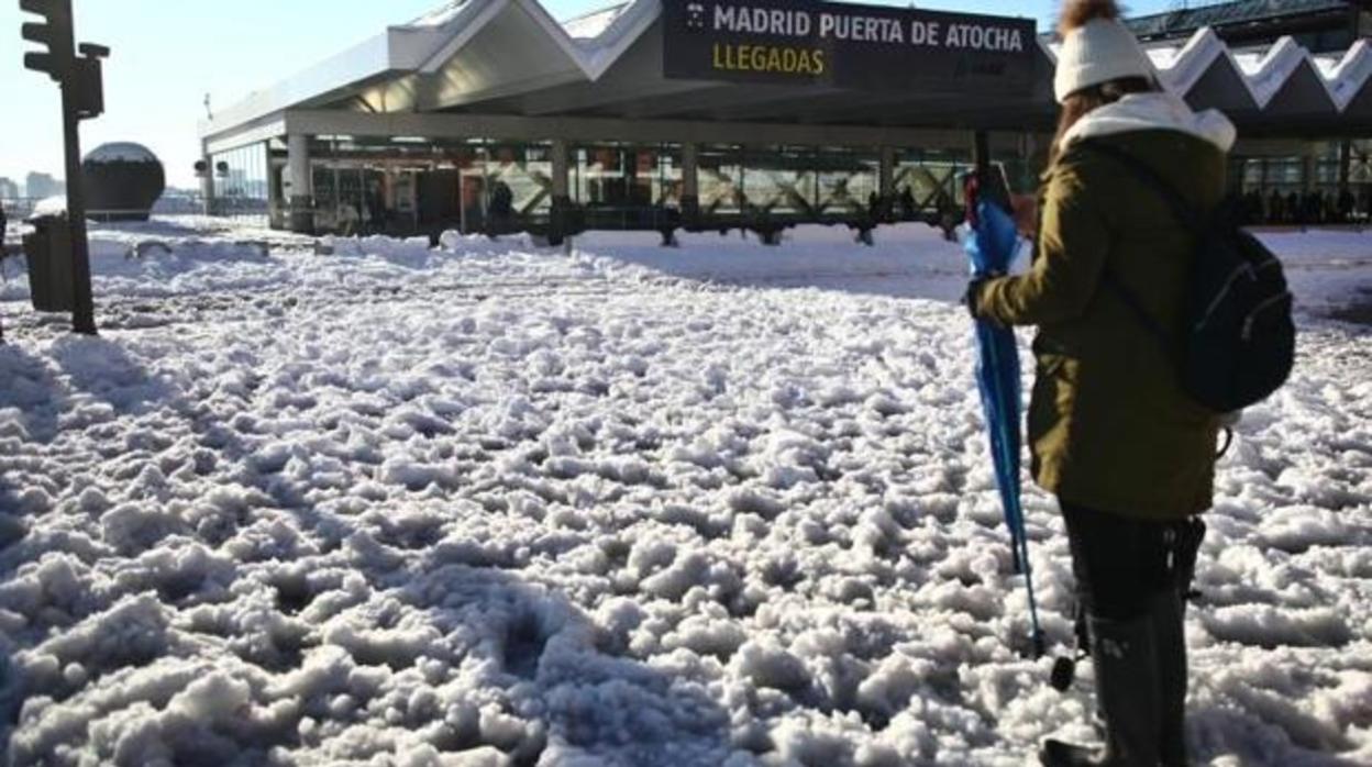 La nieve y el hielo cubren las calles de Madrid. En la imagen, una mujer cruza con cuidado un paso de cebra cubierto por la nieve congelada en Atocha