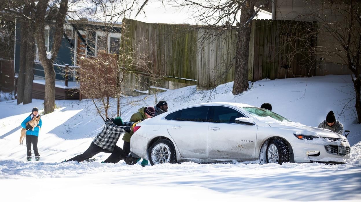 Varias personas empujan un coche atrapado por la nieve en Texas