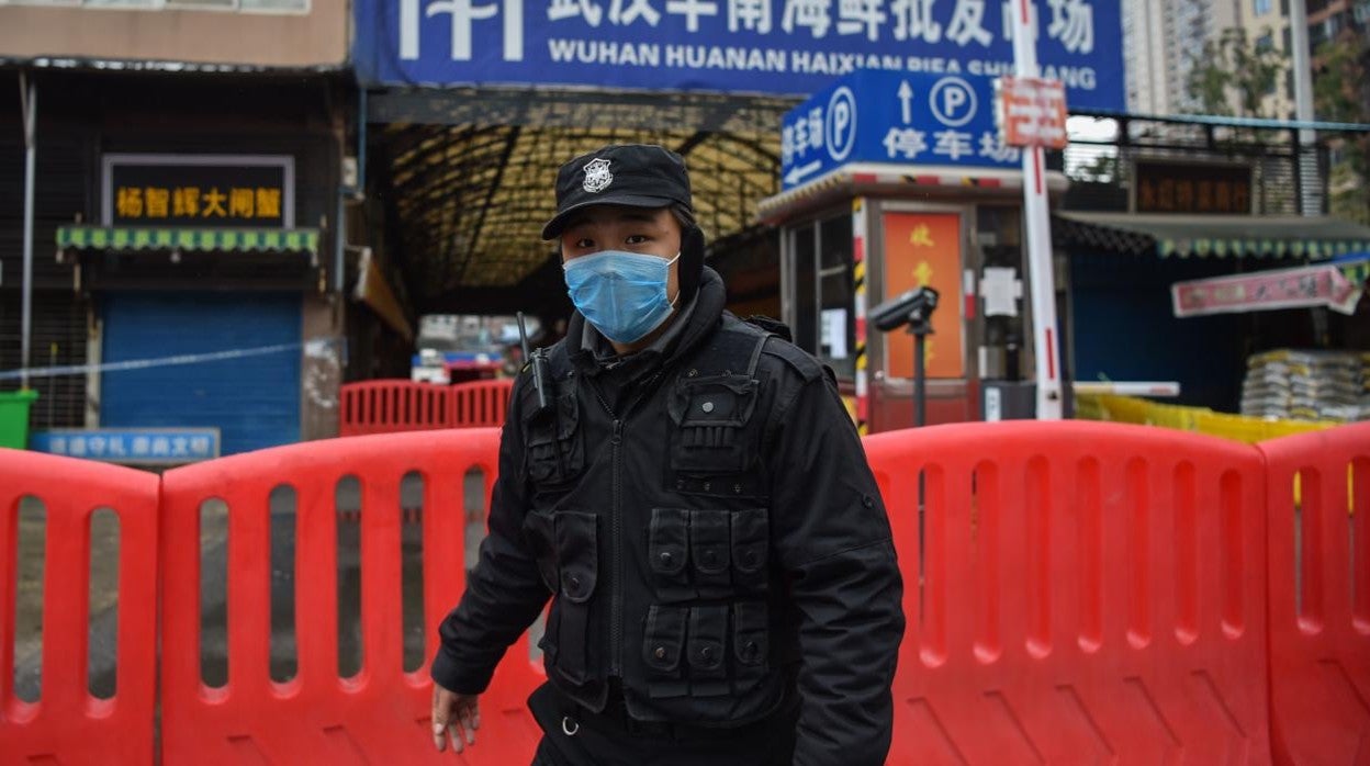 Un oficial de la policía del régimen chino trata de impedir a la prensa que fotografía el mercado de Huanan, en la ciudad de Wuhan