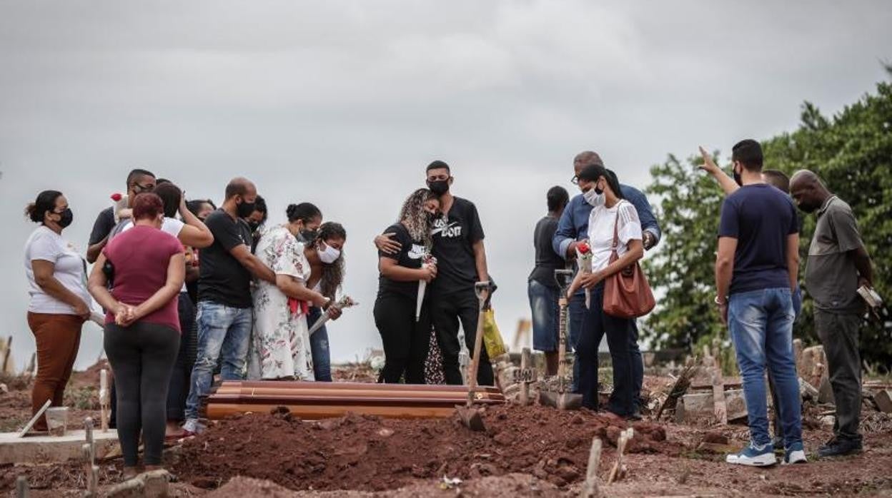 Familiares lloran la muerte por Covid-19 de un ser querido, durante su entierro en un cementerio del norte de Río de Janeiro (Brasil)