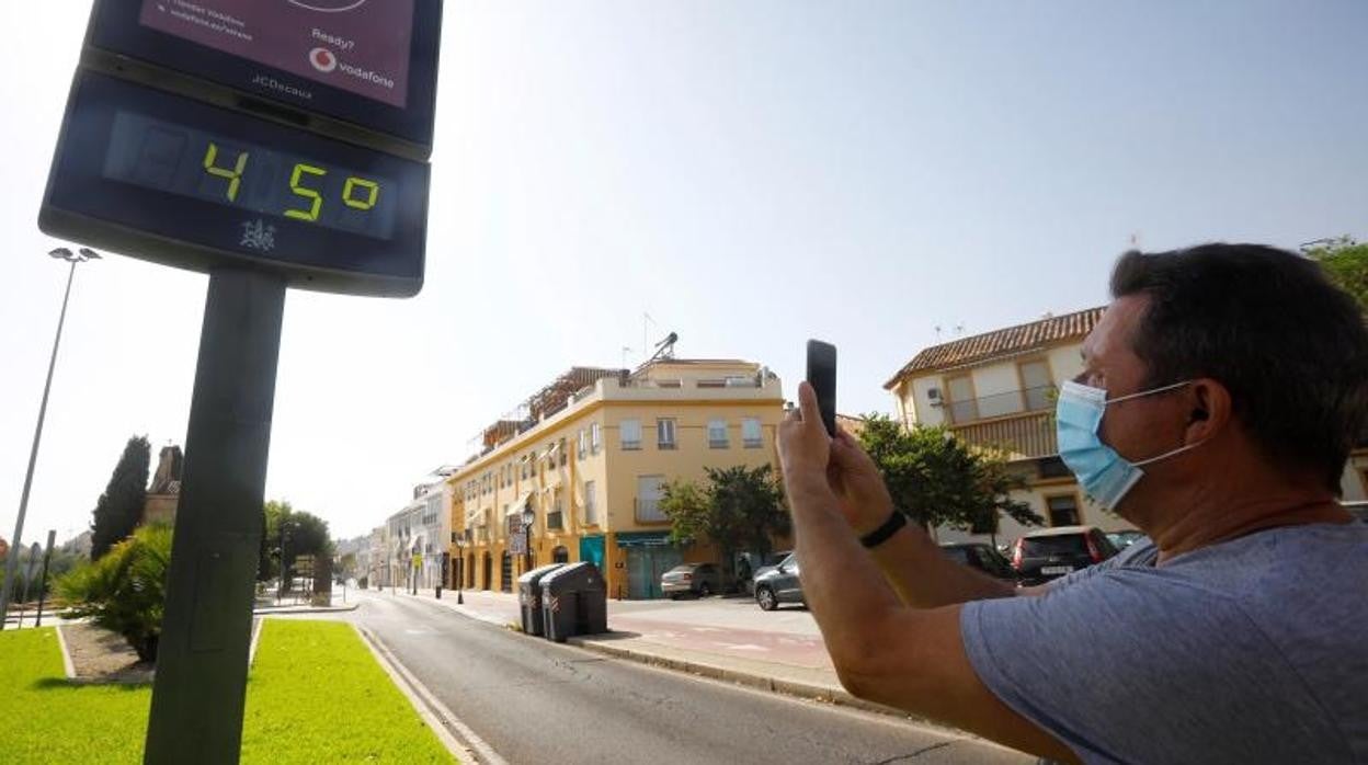 Un hombre toma una fotografía de un termómetro de Córdoba que marca los 45 grados