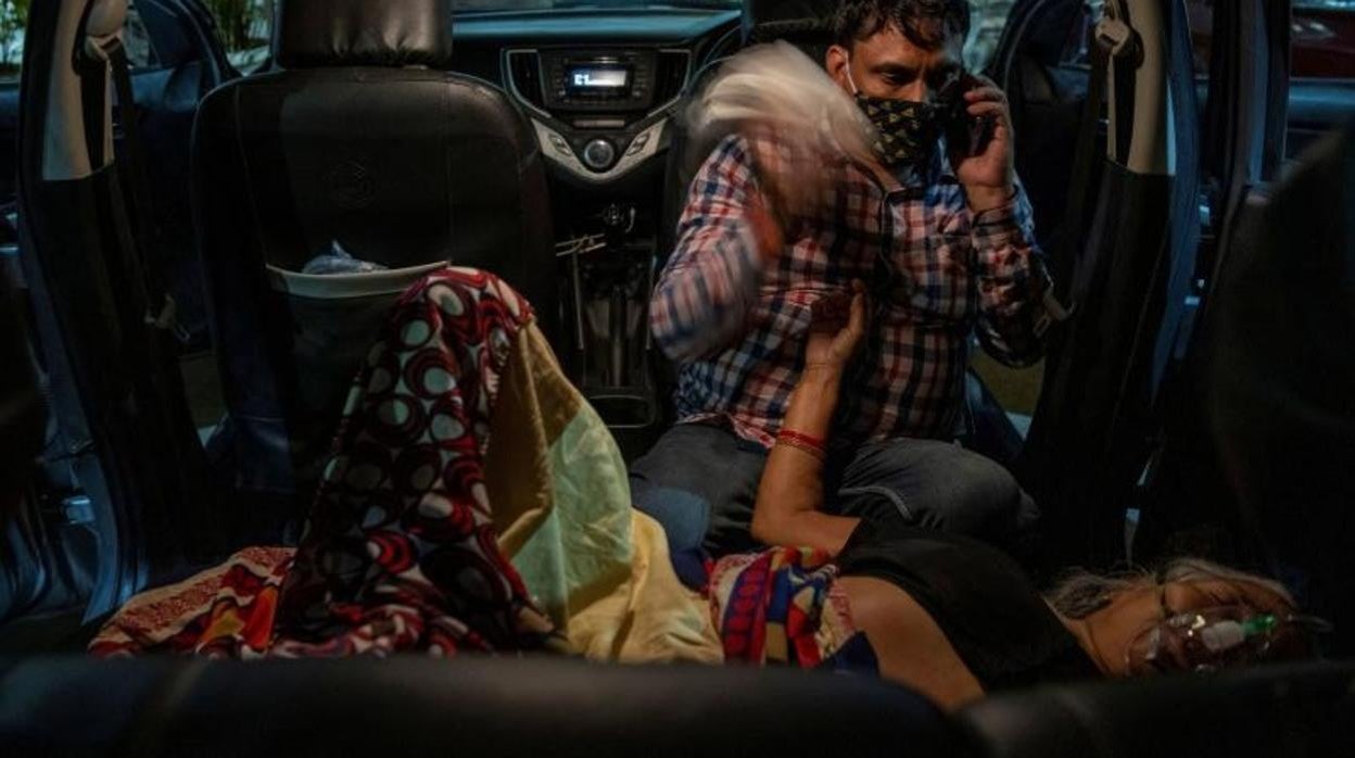 Un hombre se sienta junto a su madre mientras recibe oxígeno de forma gratuita en un Gurudwara, en Ghaziabad, India