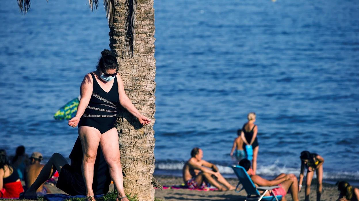 Una mujer toma el sol en Málaga, provista de mascarilla