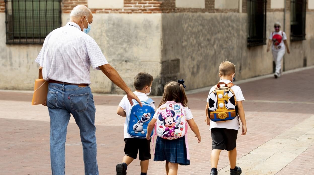 Un abuelo recoge a sus nietos del colegio en Alcalá de Henares, Madrid