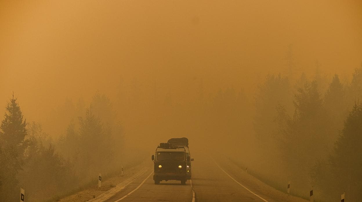 Los coches circulan por una carretera cubierta de humo de los incendios forestales cercanos entre el pueblo de Magaras y la ciudad de Yakutsk, en la República de Sajá, Siberia
