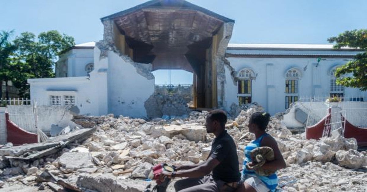 Dos personas pasan por delante de los restos de la iglesia 'Sacré coeur des Cayes', de la zona afectada por el terremoto