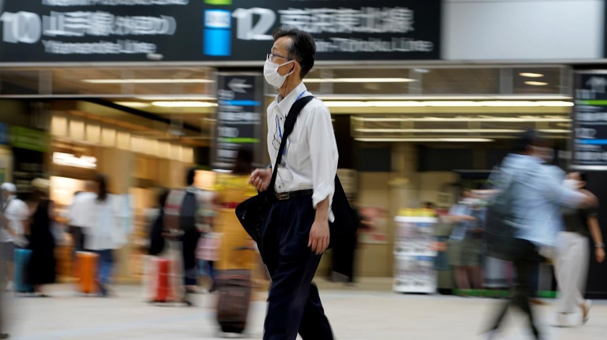 Un hombre con mascarilla camina por la estación de tren de Tokio