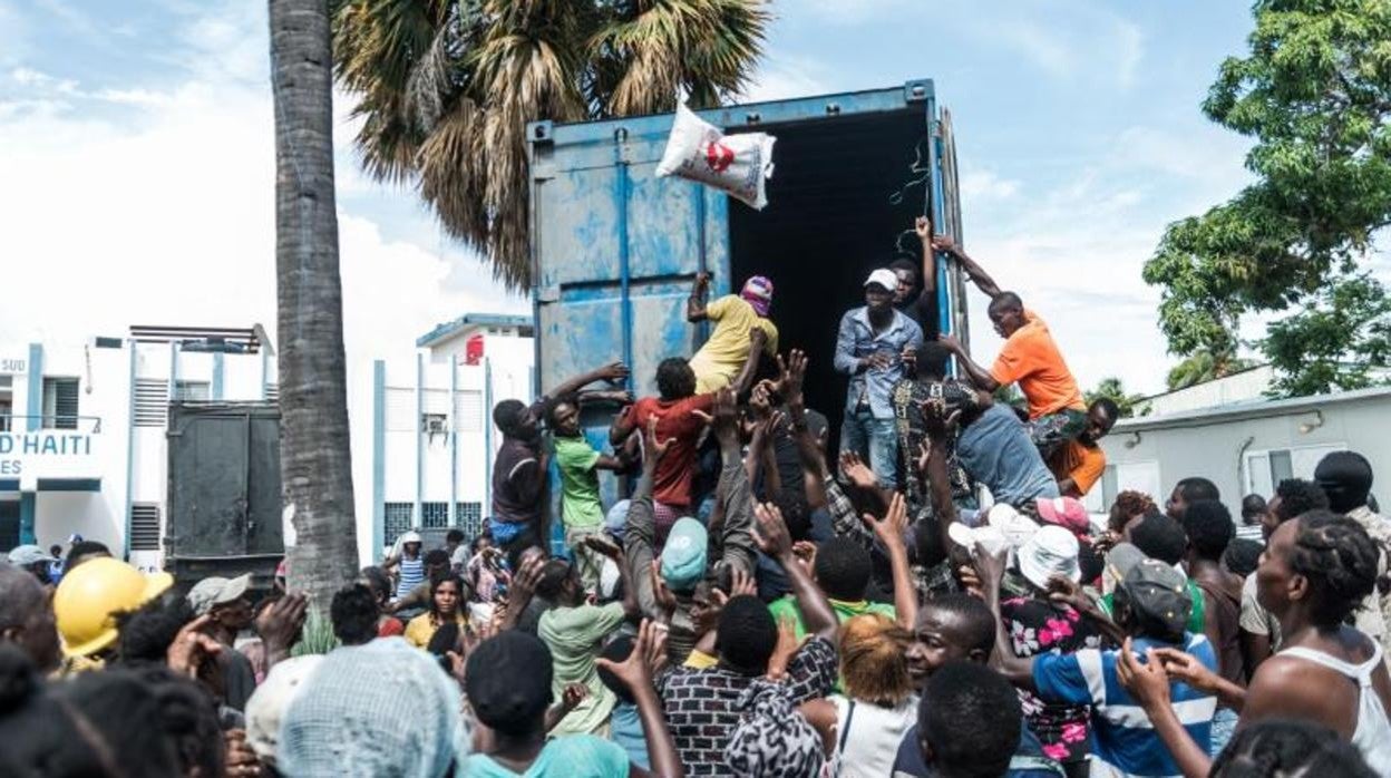 Un hombre arroja una bolsa de arroz a una multitud de personas en la localidad haitiana de Los Cayos