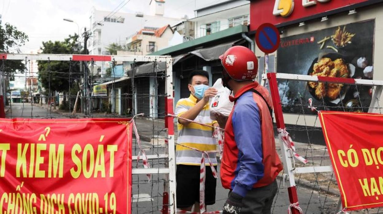 Un hombre en cuarentena recibe un paquete de comida en Ho Chi Minh