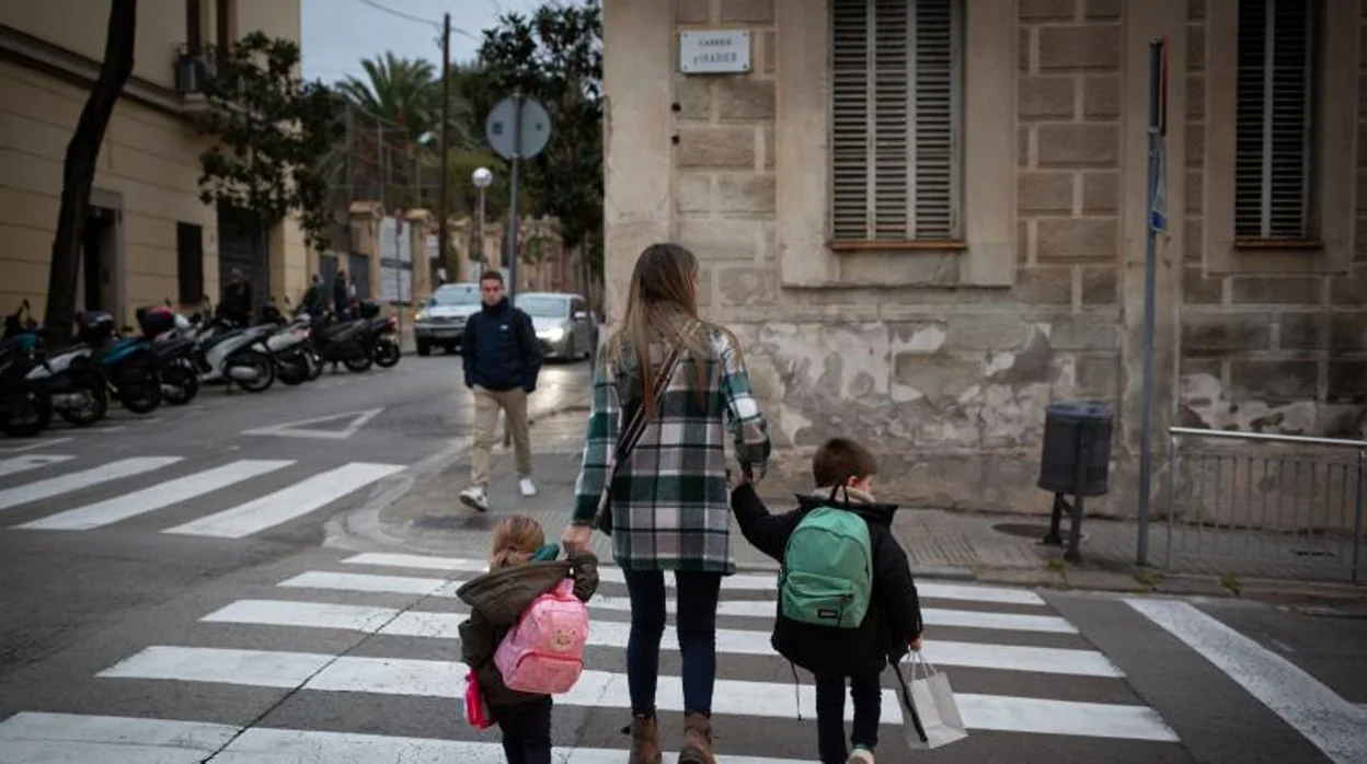 Dos niñas, de la mano de su madre, a la llegada a clases en Barcelona en plena explosión de contagios por la variante Ómicron
